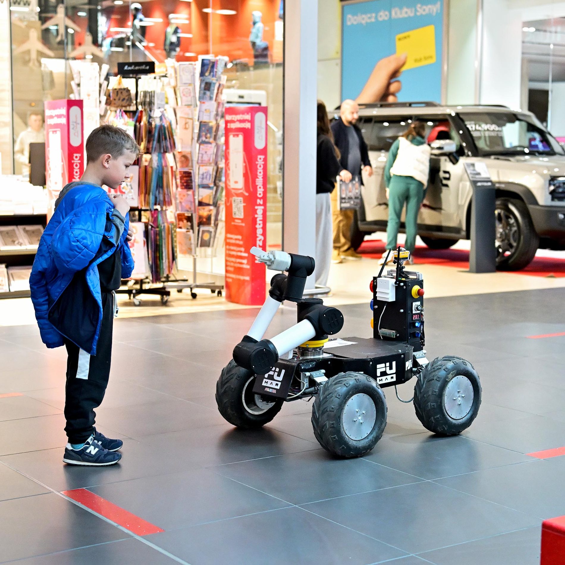 Mały chłopiec przygląda się robotowi mobilnemu PŚk podczas pokazów technologii w Galerii Echo.