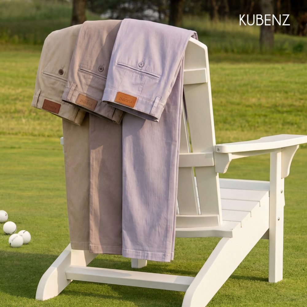 Zdjęcie promocyjne KUBENZ – trzy pary męskich spodni chinos w jasnych odcieniach przewieszone przez białe krzesło ogrodowe, ustawione na trawie w plenerze.