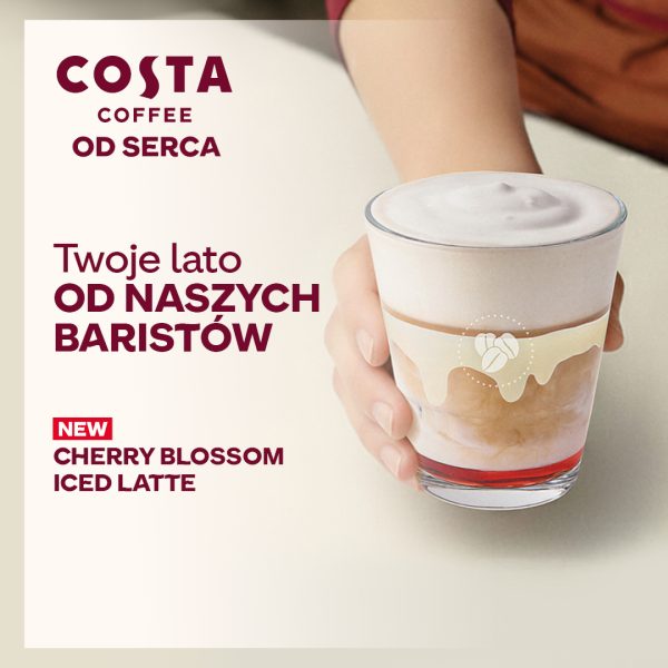 Plakat promuje letnią ofertę pod hasłem „Twoje lato od naszych baristów”, eksponując nową mrożoną kawę o smaku kwiatu wiśni. Po lewej stronie umieszczono logotyp Costa Coffee z dopiskiem „Od serca” oraz nazwę nowego napoju wyróżnioną czerwonym napisem „NEW”.