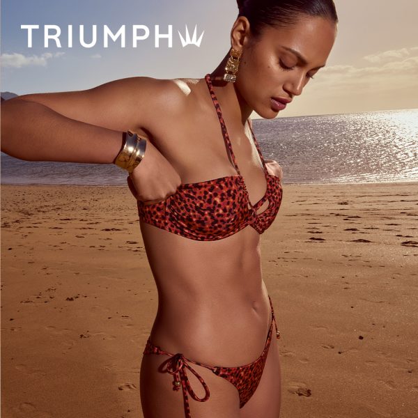 Plakat promocyjny marki Triumph z hasłem Życie w golden hour, przedstawiający modelkę w luksusowym kostiumie kąpielowym na plaży
