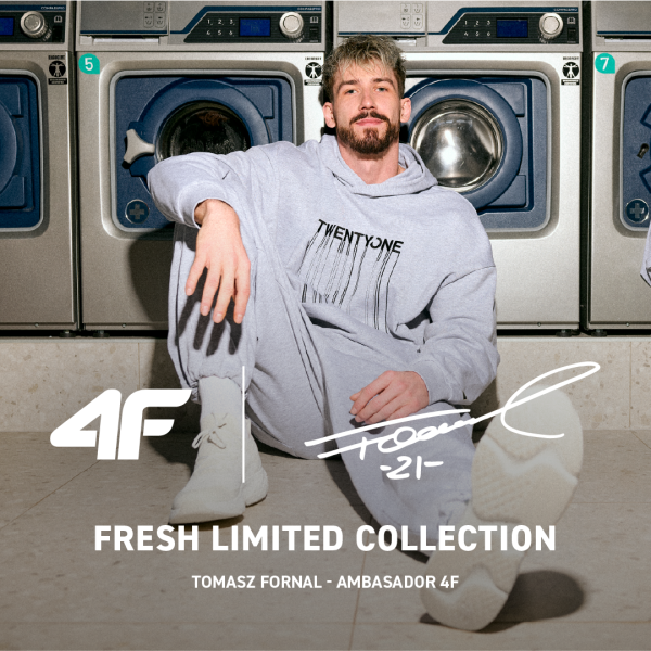 Zdjęcie reklamowe nowej kolekcji odzieżowej 4F x Tomasz Fornal w salonie 4F w Galerii Echo. Siatkarz Tomasz Fornal siedzi na podłodze w pralni samoobsługowej ubrany w szary dresowy komplet z kapturem z czarnym napisem TWENTYONE i jasne buty sportowe. W tle widać pralki automatyczne. Na dole umieszczono białe logo 4F, podpis siatkarza z numerem 21 oraz napis FRESH LIMITED COLLECTION TOMASZ FORNAL - AMBASADOR 4F.