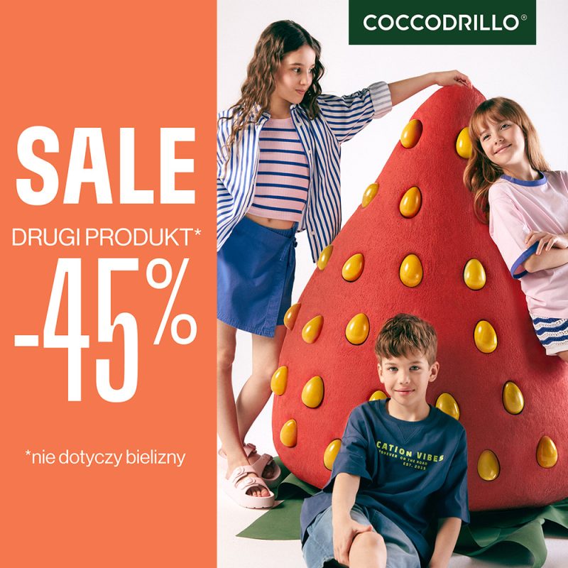 Zdjęcie promocyjne marki Coccodrillo przedstawia troje dzieci pozujących przy dużej figurze truskawki. Po lewej stronie, na pomarańczowym tle, umieszczono duży napis informujący o wyprzedaży i rabacie -45% na drugi produkt.