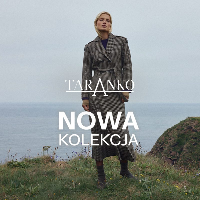 Kwadratowe zdjęcie wizerunkowe marki Taranko z widoczną blond modelką stojącą na zielonym klifie nad morzem. Modelka ma na sobie długi, dwurzędowy płaszcz w drobną kratkę wiązany w pasie. Na środku znajduje się białe logo TARANKO oraz duży biały napis NOWA KOLEKCJA.