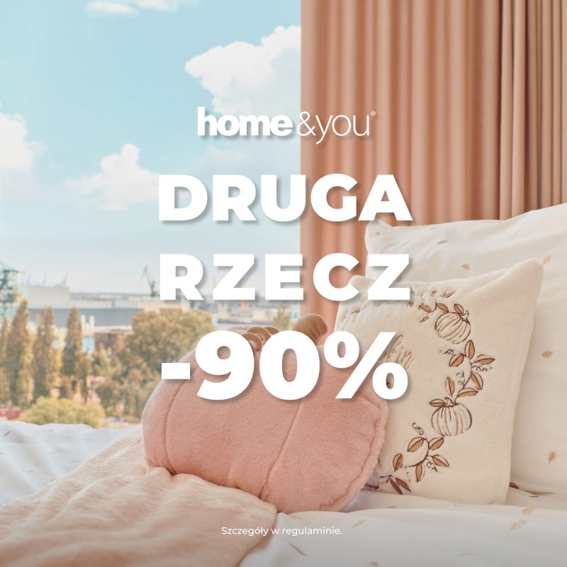 Kwadratowa grafika promocyjna marki home&you przedstawiająca przytulną sypialnię. Na łóżku z wzorzystą, jasną pośpielą leży różowy koc i dekoracyjne poduszki w kształcie dyni. W tle za łóżkiem okno z widokiem na miasto i beżowo-różowa zasłona. Na pierwszym planie białe logo home&you oraz duży biały napis DRUGA RZECZ -90%.