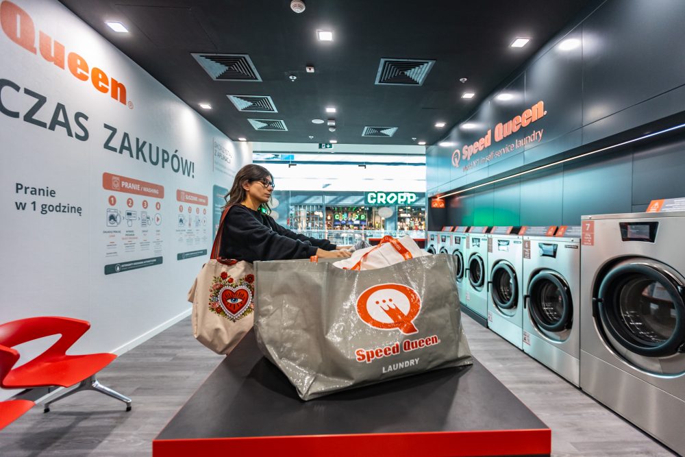 Kobieta pakująca pranie w nowoczesnym wnętrzu pralni Speed Queen w Galerii Echo.