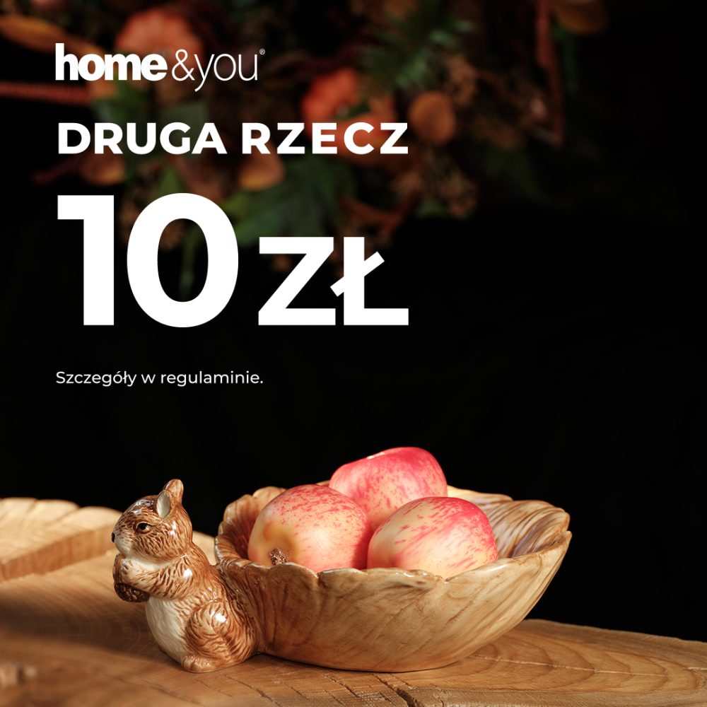 Kwadratowa grafika reklamowa marki home&you utrzymana w jesiennym klimacie. Na ciemnym tle widnieje białe logo home&you, napis DRUGA RZECZ 10 zł oraz informacja Szczegóły w regulaminie. W dolnej części zdjęcia na drewnianym stole widać ceramiczne pojemniki i miseczki w kształcie liści z figurkami wiewiórek, w tym jedną miseczkę wypełnioną czerwonymi jabłkami.