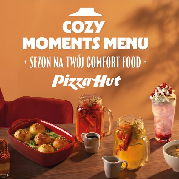 Grafika promocyjna marki Pizza Hurt prezentująca menu „Cozy Moments Menu – sezon na twój comfort food”. Na ciepłym, pomarańczowym tle oraz drewnianym stole widoczne są pyszne potrawy i napoje: zapiekane bułeczki w czerwonym naczyniu, rozgrzewające napary w szklanych słoikach z uszkiem, deser z bitą śmietaną oraz zupa. W górnej części znajduje się logo Pizza Hut oraz białe napisy promocyjne.