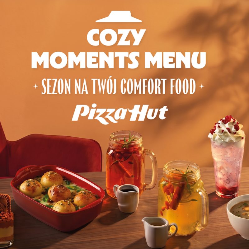 Grafika promocyjna marki Pizza Hurt prezentująca menu „Cozy Moments Menu – sezon na twój comfort food”. Na ciepłym, pomarańczowym tle oraz drewnianym stole widoczne są pyszne potrawy i napoje: zapiekane bułeczki w czerwonym naczyniu, rozgrzewające napary w szklanych słoikach z uszkiem, deser z bitą śmietaną oraz zupa. W górnej części znajduje się logo Pizza Hut oraz białe napisy promocyjne.