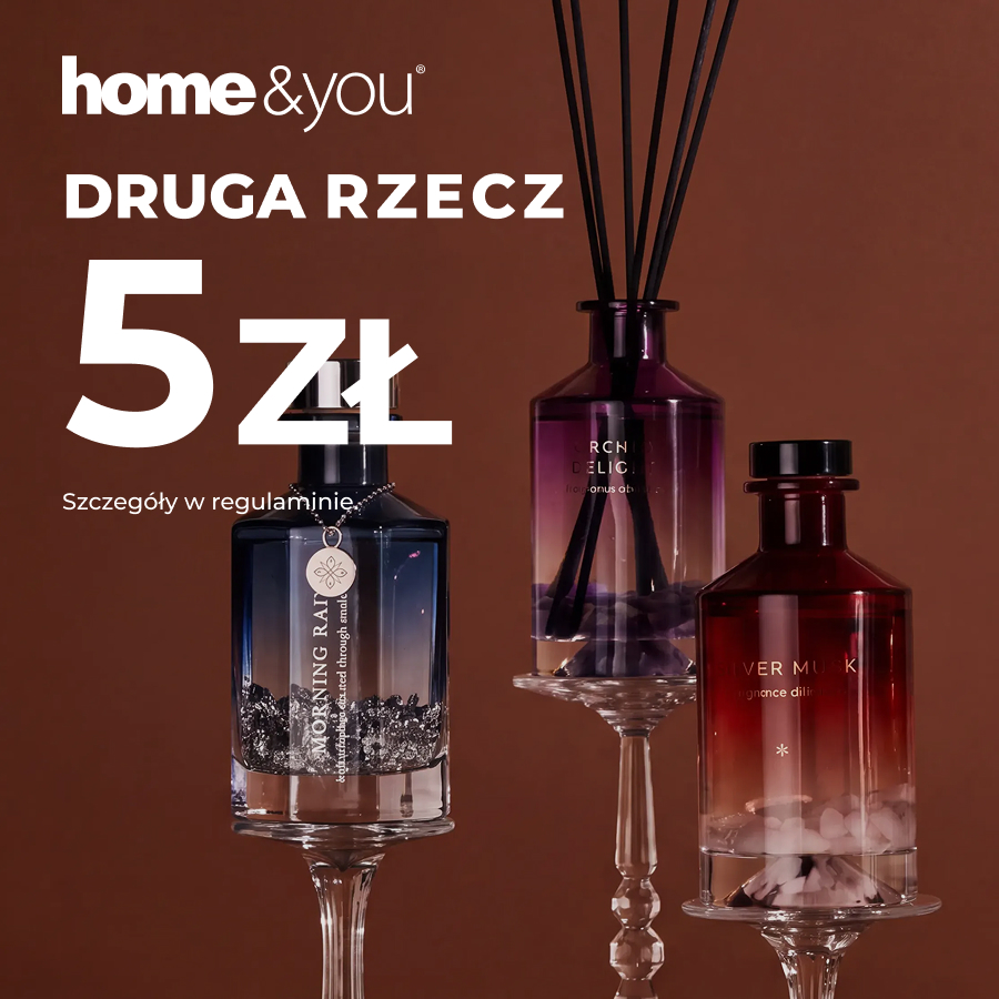 Fioletowy dyfuzor z czarnymi patyczkami między granatowym i bordowym flakonem z ozdobnymi kamieniami, na wysokich szklanych podstawkach i brązowym tle